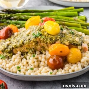 One-Pan Salmon and Roasted Asparagus Recipe 14 Plate with couscous, roasted asparagus, cherry tomatoes, and pesto-topped salmon.