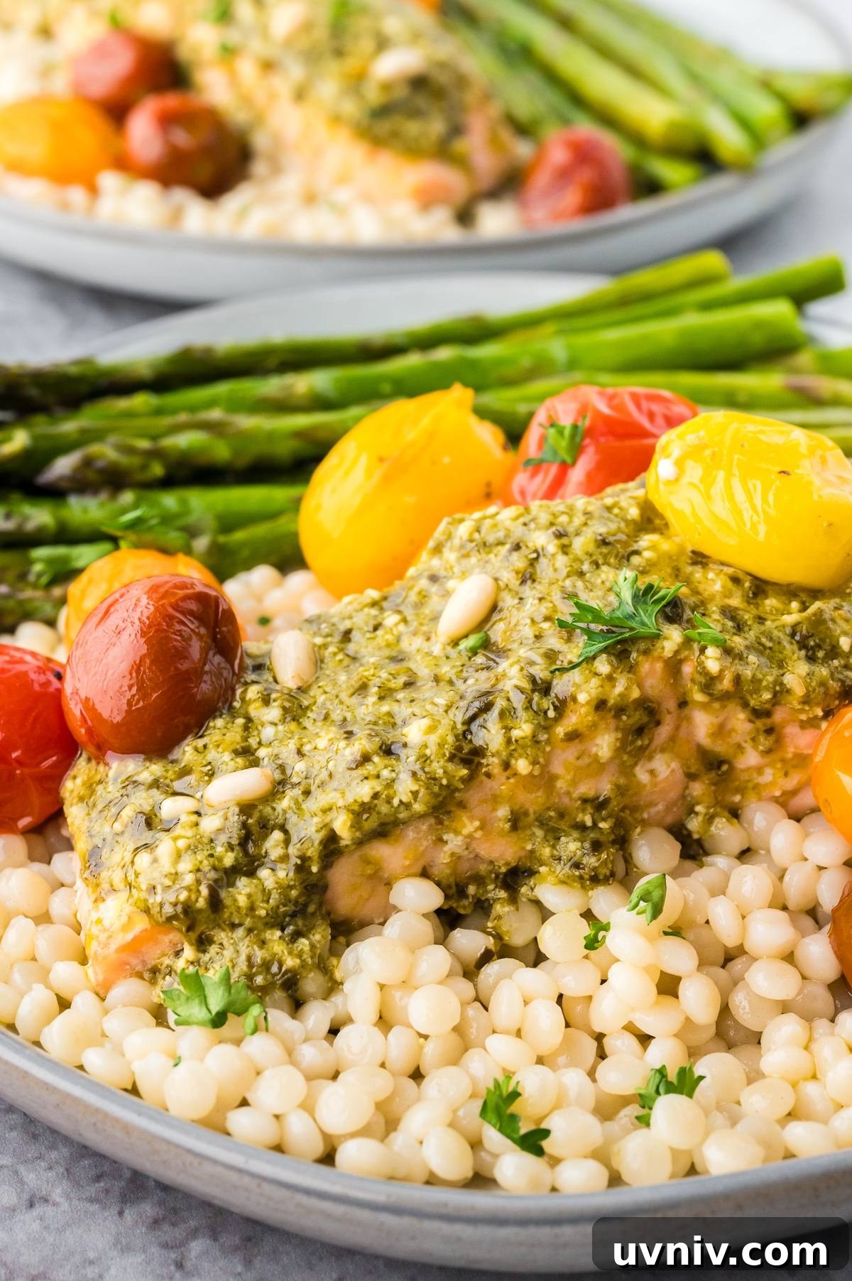 One-Pan Salmon and Roasted Asparagus Recipe 8 Salmon with pesto, couscous, roasted tomatoes, and asparagus on a plate.