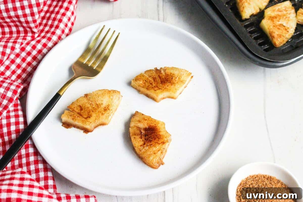 Crispy Caramelized Pineapple in the Air Fryer 2 A plate with slices of air fryer pineapple on it next to a fork.