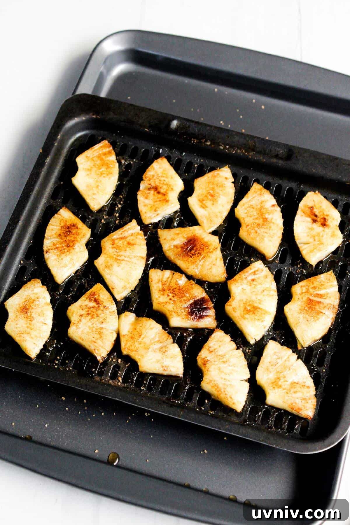 Crispy Caramelized Pineapple in the Air Fryer 11 Grilled pineapple slices on an air fryer tray.