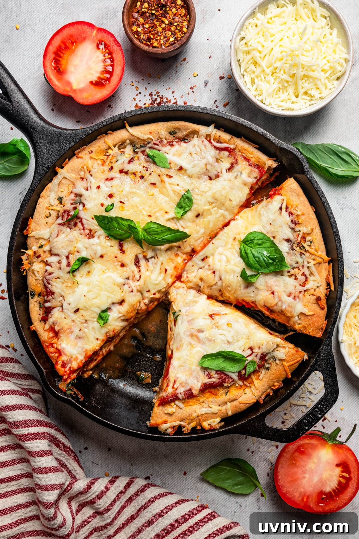 This deep dish pizza recipe with homemade herbed crust, tomatoes, and lots of melty cheese will bring Pizza Night to your kitchen each week. Overhead image of a deep dish pizza in a skillet.
