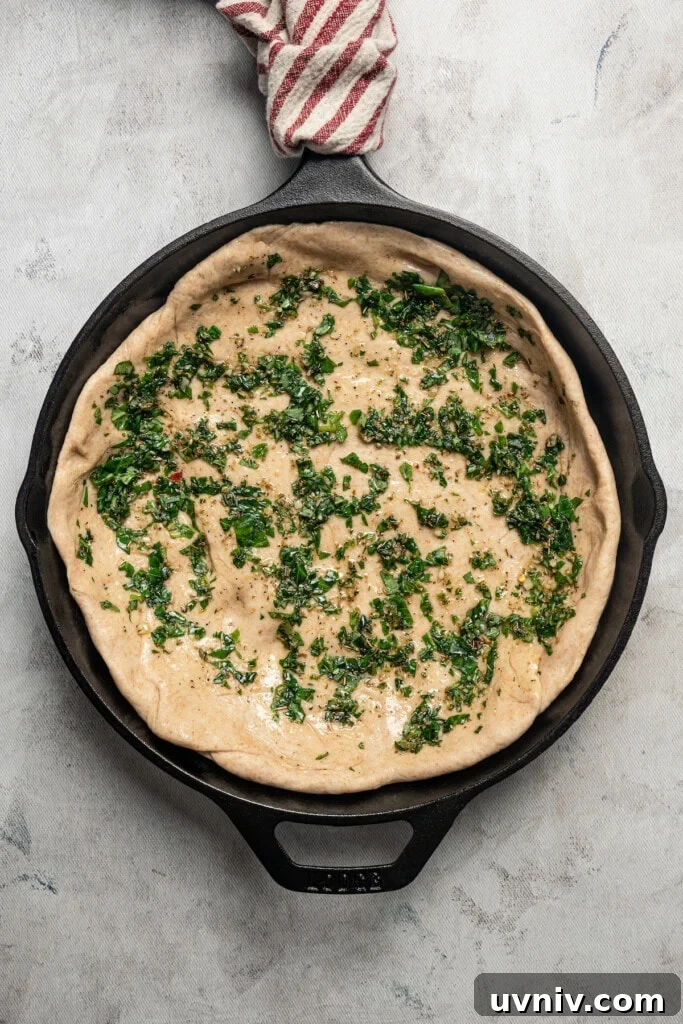 This deep dish pizza recipe with homemade herbed crust, tomatoes, and lots of melty cheese will bring Pizza Night to your kitchen each week. Brushing the herby garlic oil over the dough.