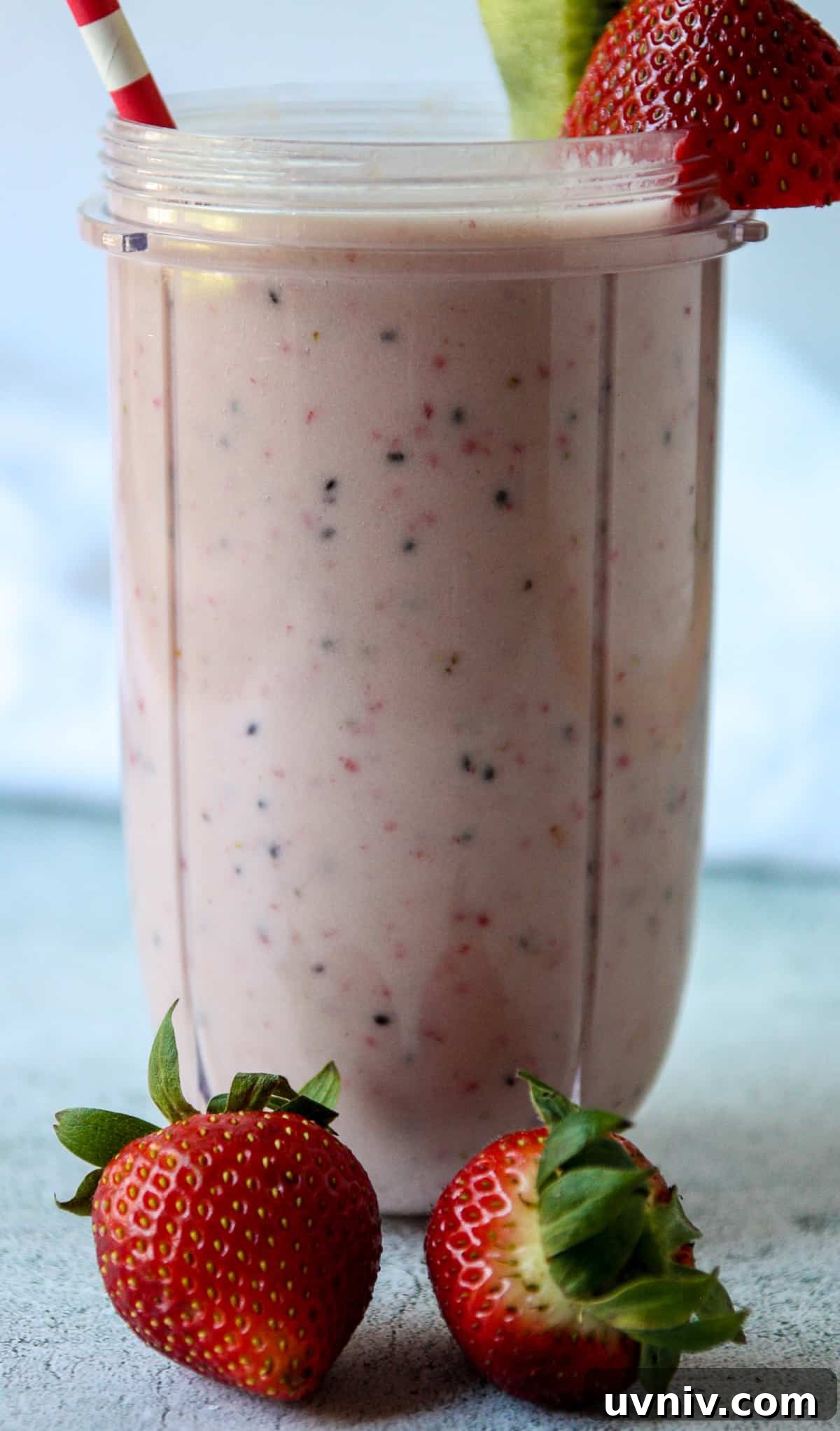 Pink colored kiwi quencher tropical smoothie in a tall glass.