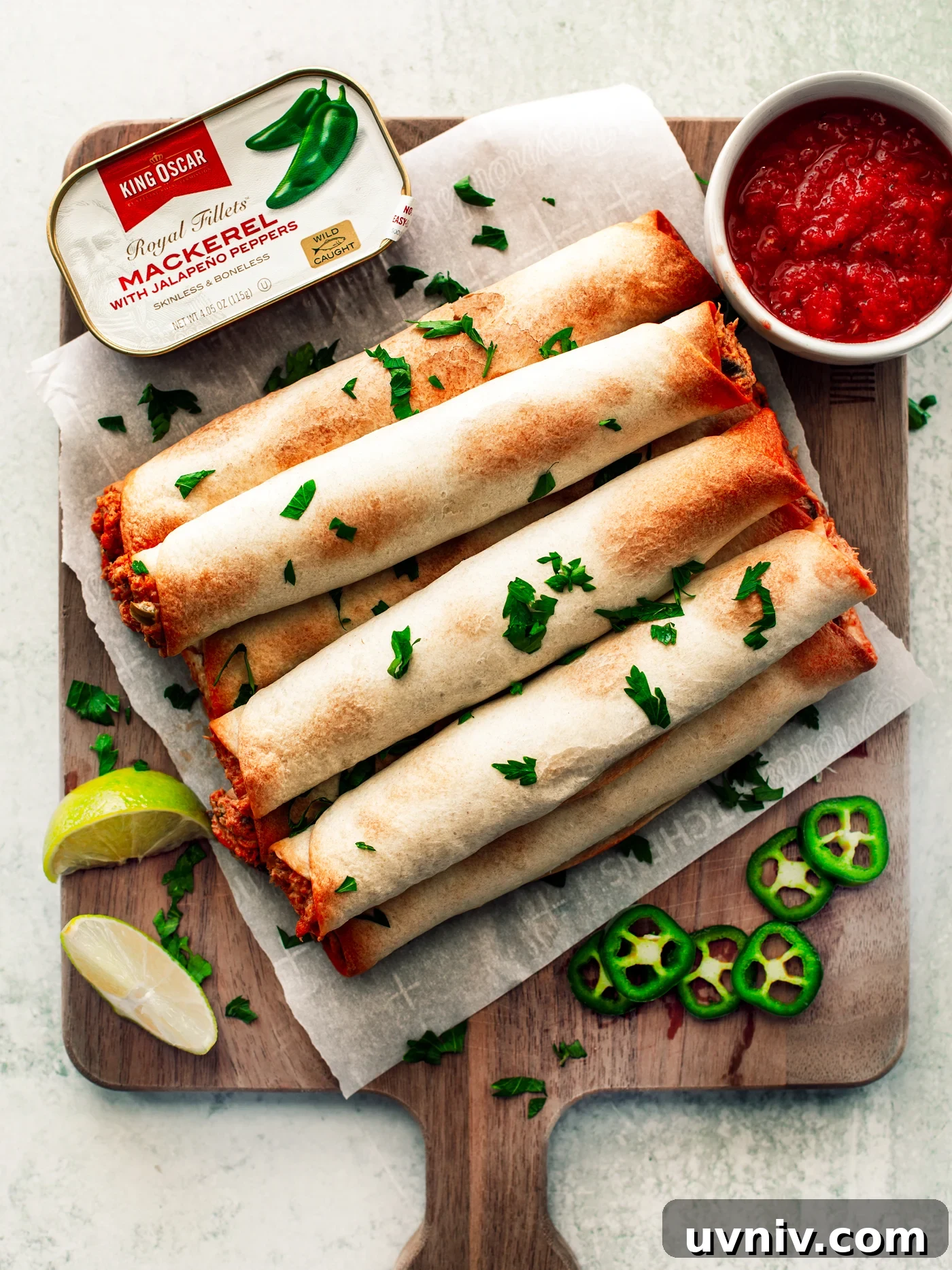 Flautas on a wooden serving board with a side of salsa and tin of King Oscar mackerel