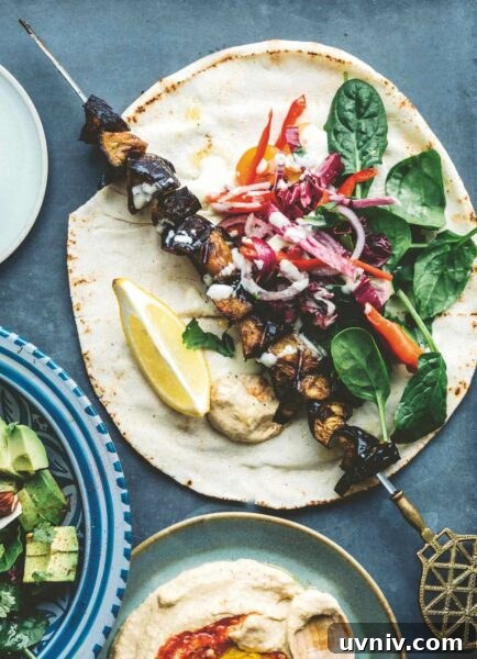 An eggplant kebab on a tortilla with fresh spinach, garlic sauce, and cabbage.
