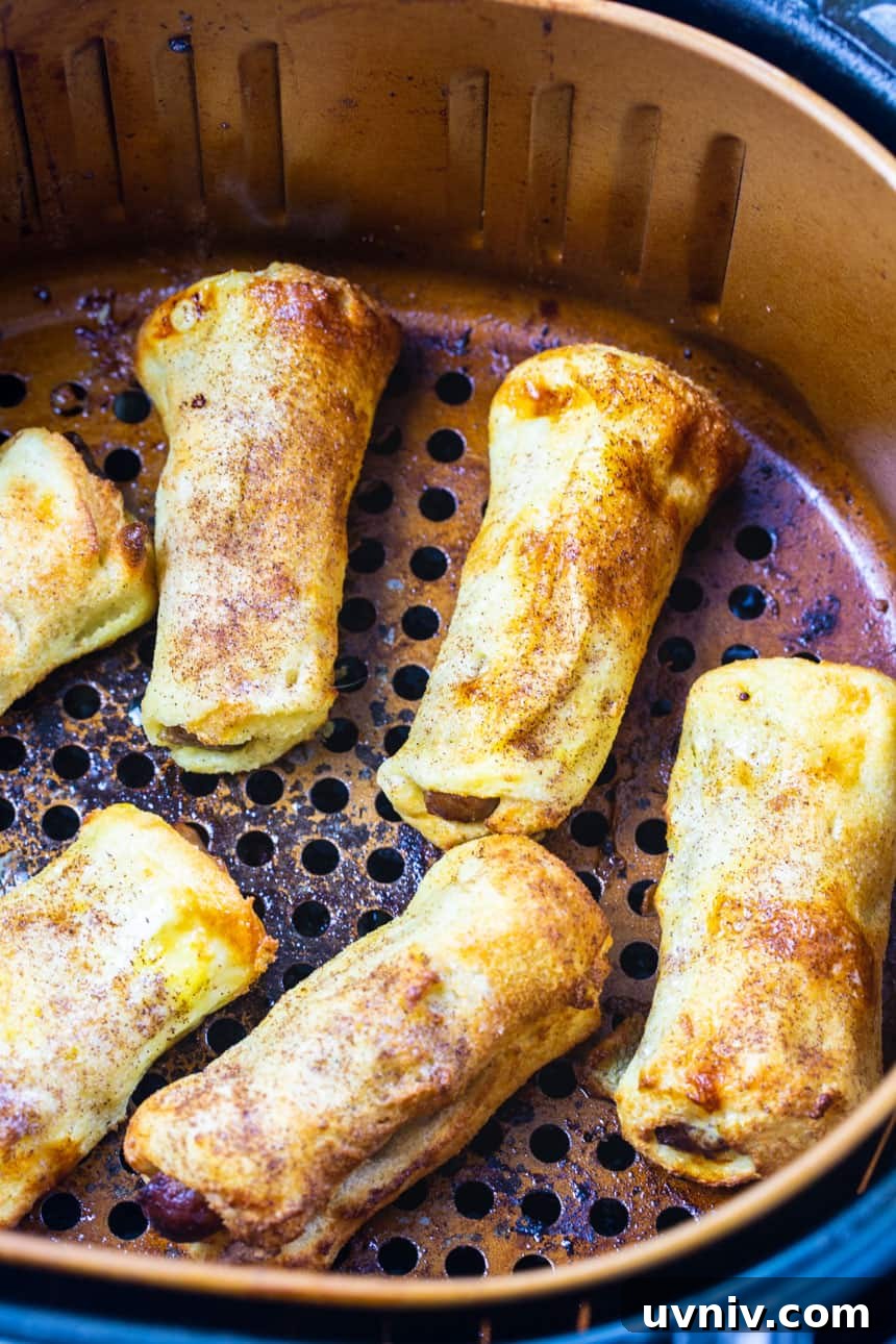 Air Fryer Sausage and French Toast Roll-Ups: Quick Breakfast Recipe 3 French Toast sausage Roll-Ups in air fryer basket.