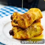Air Fryer Sausage and French Toast Roll-Ups: Quick Breakfast Recipe 5 Three French Toast Roll-Ups on a plate getting drizzled with syrup.