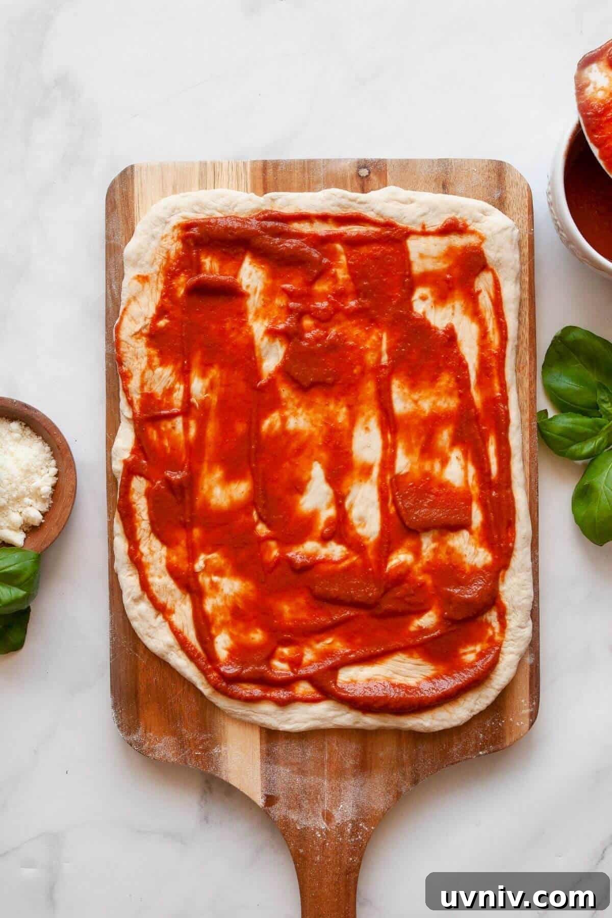 Crispy Air Fryer Pizza Rolls You Can Make at Home 4 Rolling out pizza dough and spreading marinara sauce for homemade air fryer pizza rolls.