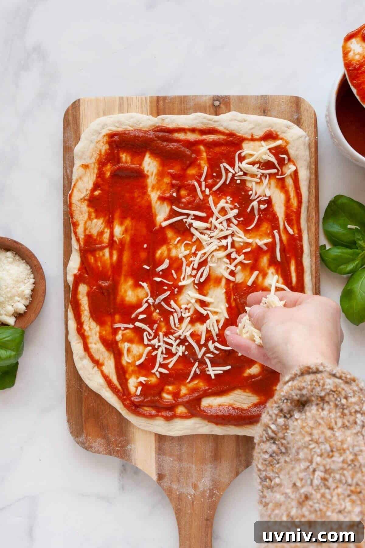 Crispy Air Fryer Pizza Rolls You Can Make at Home 5 Adding mozzarella cheese on pizza dough with marinara for homemade air fryer pizza rolls.