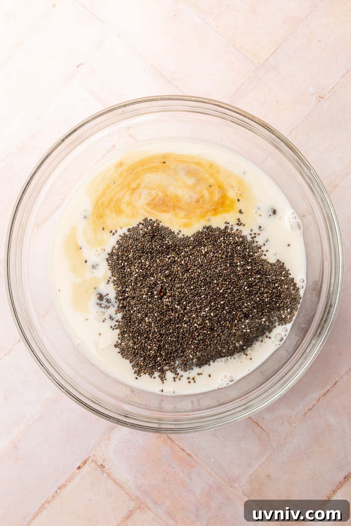 Creamy Chia Pudding Breakfast Bowl with Fresh Fruit & Nuts 4 A glass mixing bowl with almond milk, chia seeds, vanilla extract and pure maple syrup before whisking together.