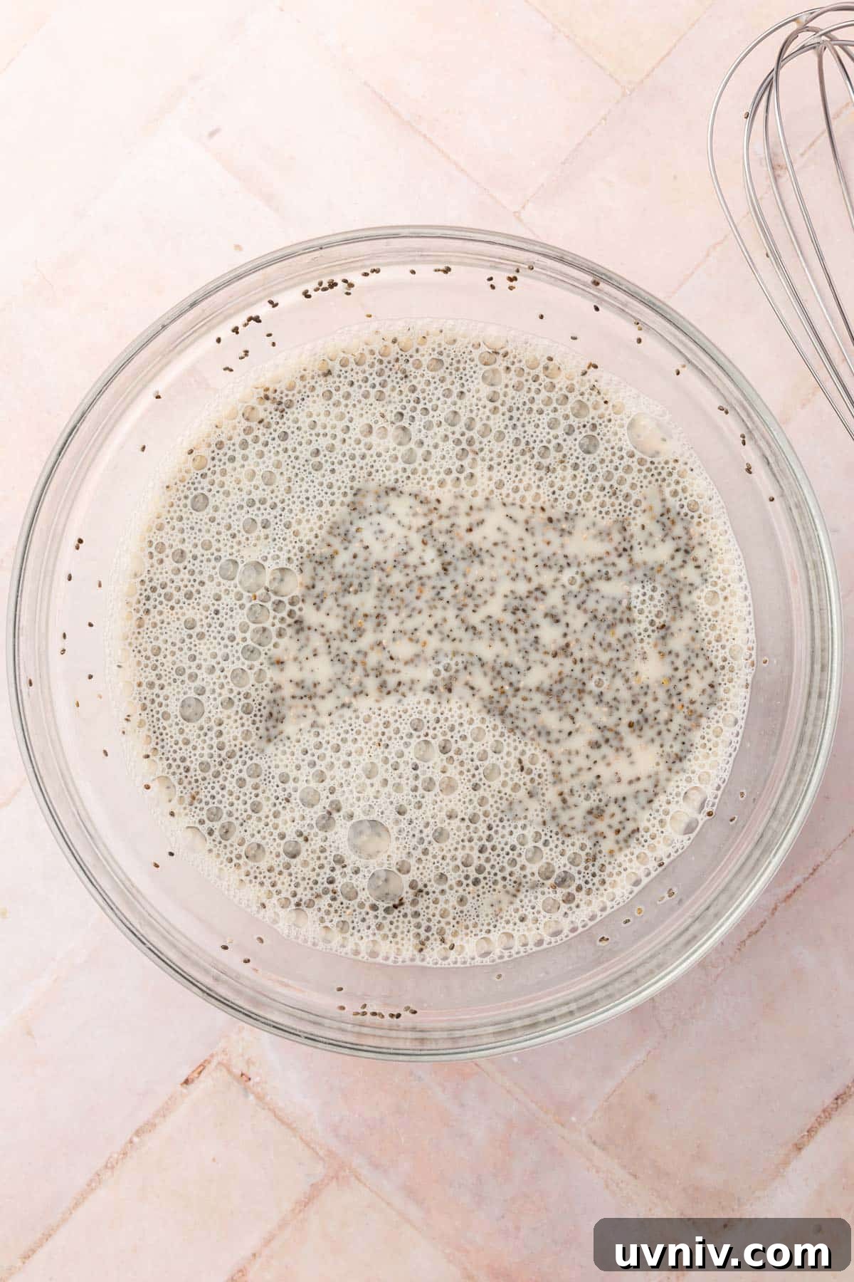 Creamy Chia Pudding Breakfast Bowl with Fresh Fruit & Nuts 5 A glass mixing bowl of almond milk and chia seeds that have been whisked together before chilling in the refrigerator.