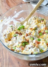 Creamy Loaded Potato Salad Made in the Instant Pot 22 loaded baked potato salad in a clear bowl with a wooden spoon