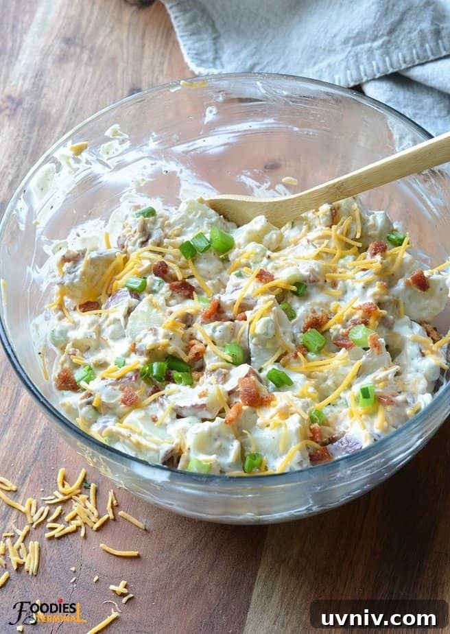 Creamy Loaded Potato Salad Made in the Instant Pot 4 loaded baked potato salad in a clear large bowl with a wooden spoon