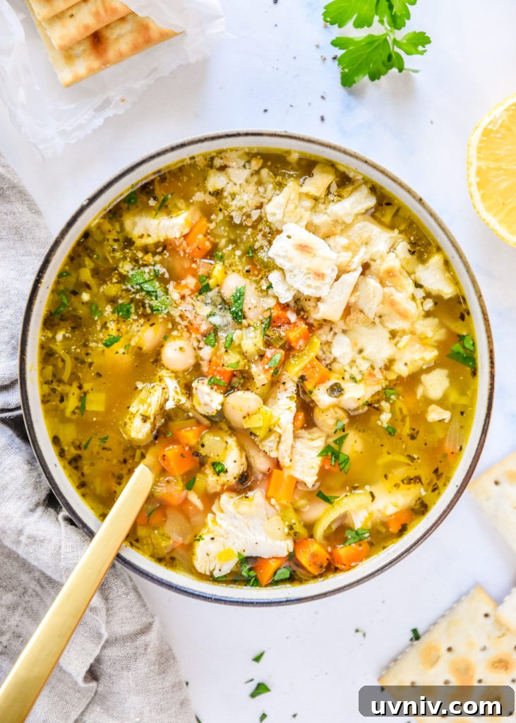 white bean lemon chicken soup in a bowl with saltine crackers on top.