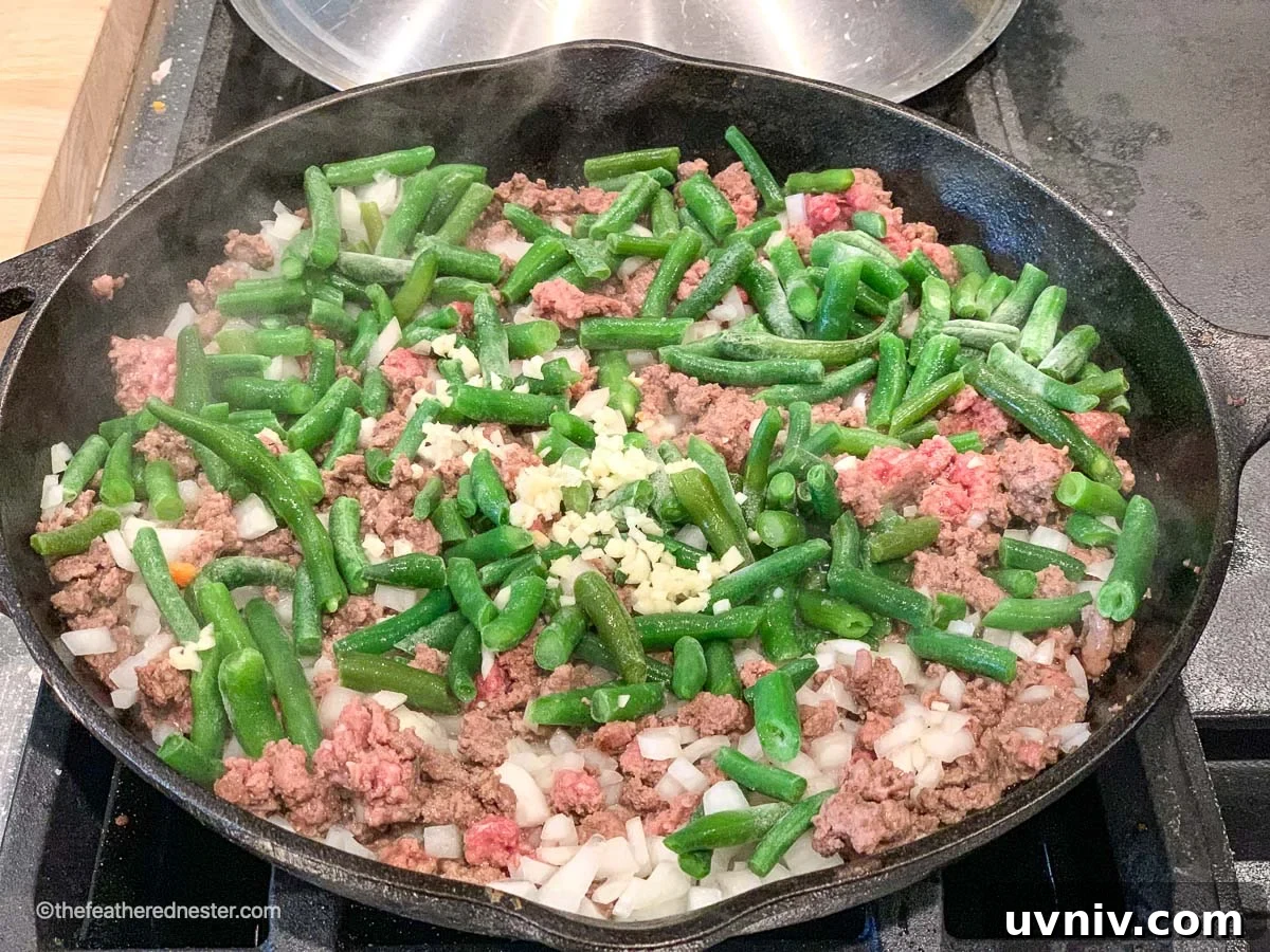 Comforting Tater Tot Casserole with Green Beans and Cheese 5 a skillet of ground beef, green beans and onions sautéing.