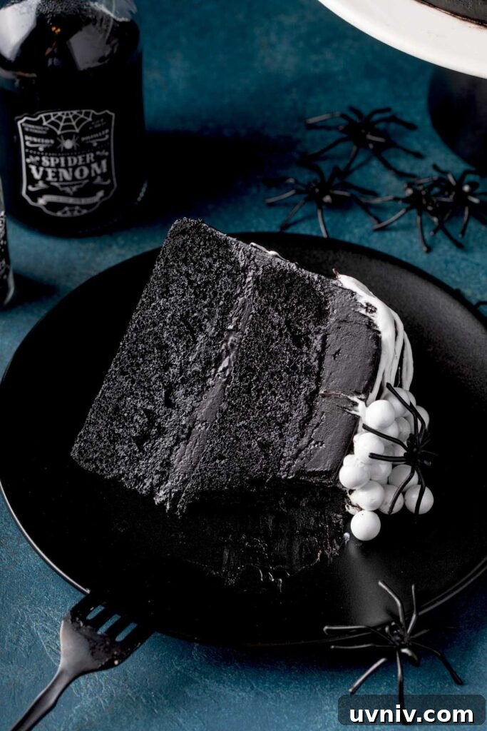 Slice of layered black velvet cake served on a black plate.