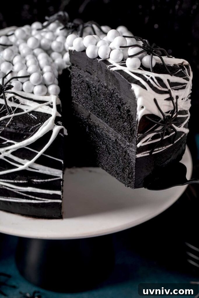 A piece of black velvet cake getting served from a cake stand
