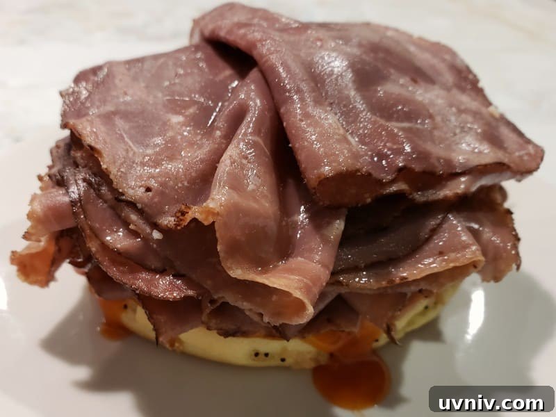 Make-Ahead Arby’s-Style Beef & Cheddar Sandwich Recipe 4 a bottom half of bun with red dressing and roast beef slices on top