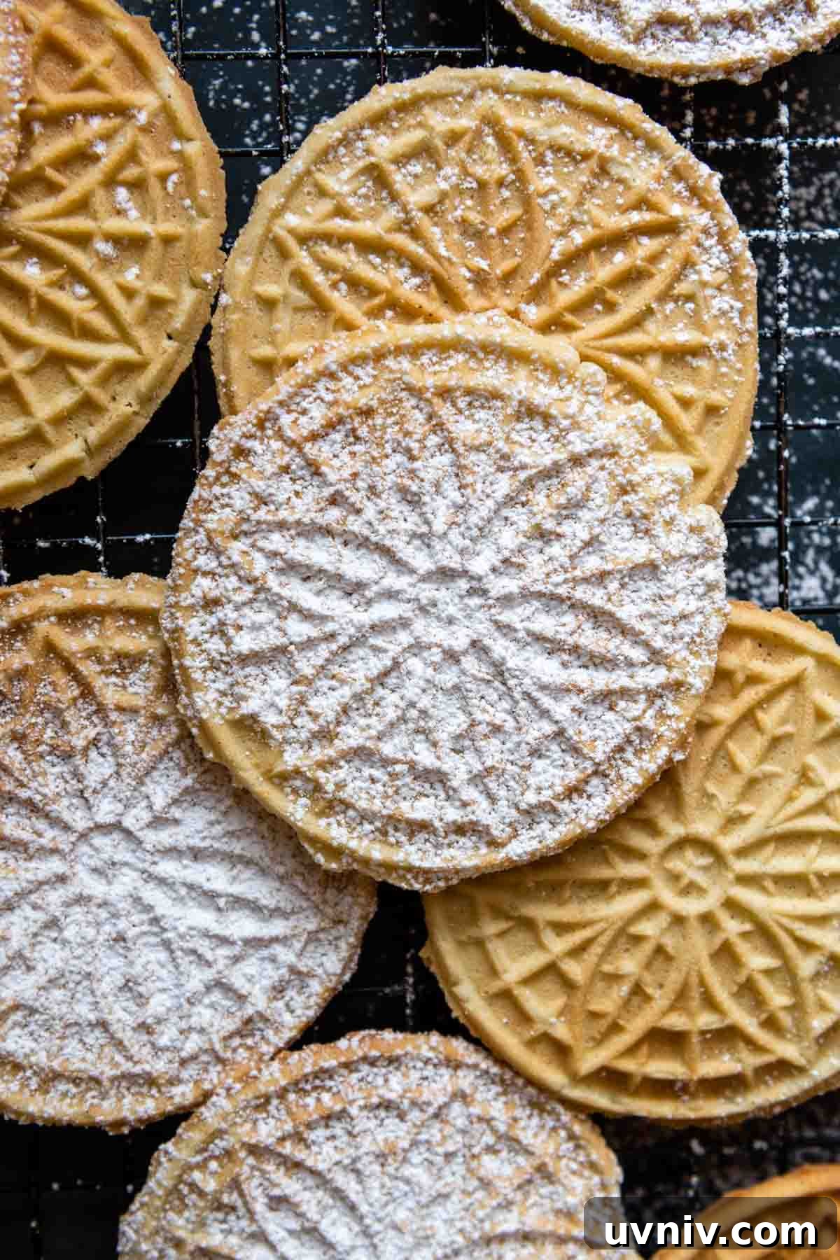 overhead shot of pizzelles with powdered sugar on a cooling rack.