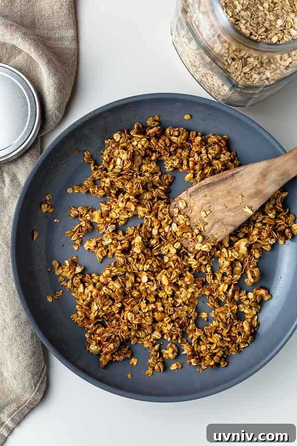 Crispy Oven-Baked Granola Without Oil: Crunchy Homemade Recipe 5 stirring homemade granola after maple syrup was added
