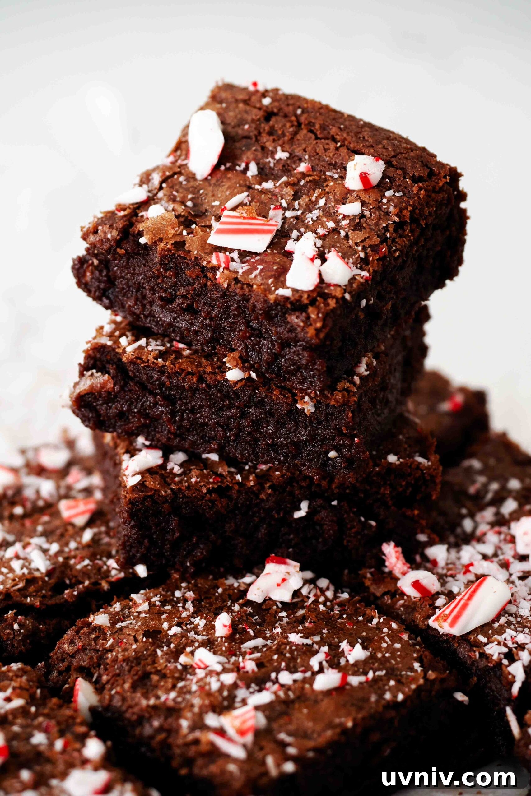 Decadent Peppermint Brownies Recipe for Holiday Baking 2 A stack of three peppermint brownies on top of a pan of brownies.