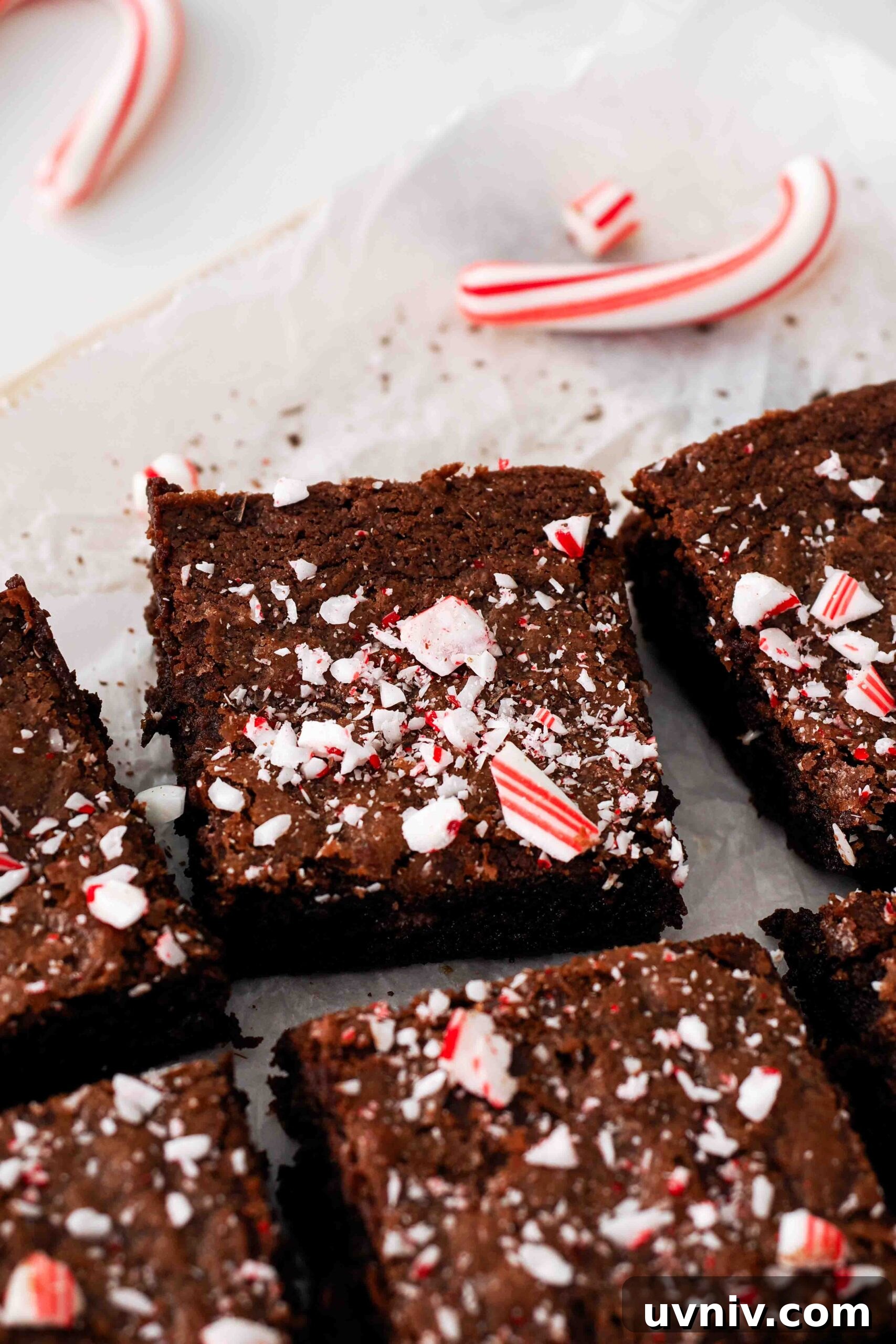 Decadent Peppermint Brownies Recipe for Holiday Baking 16 An edge brownie piece on a crumpled sheet of parchment with a candy cane.