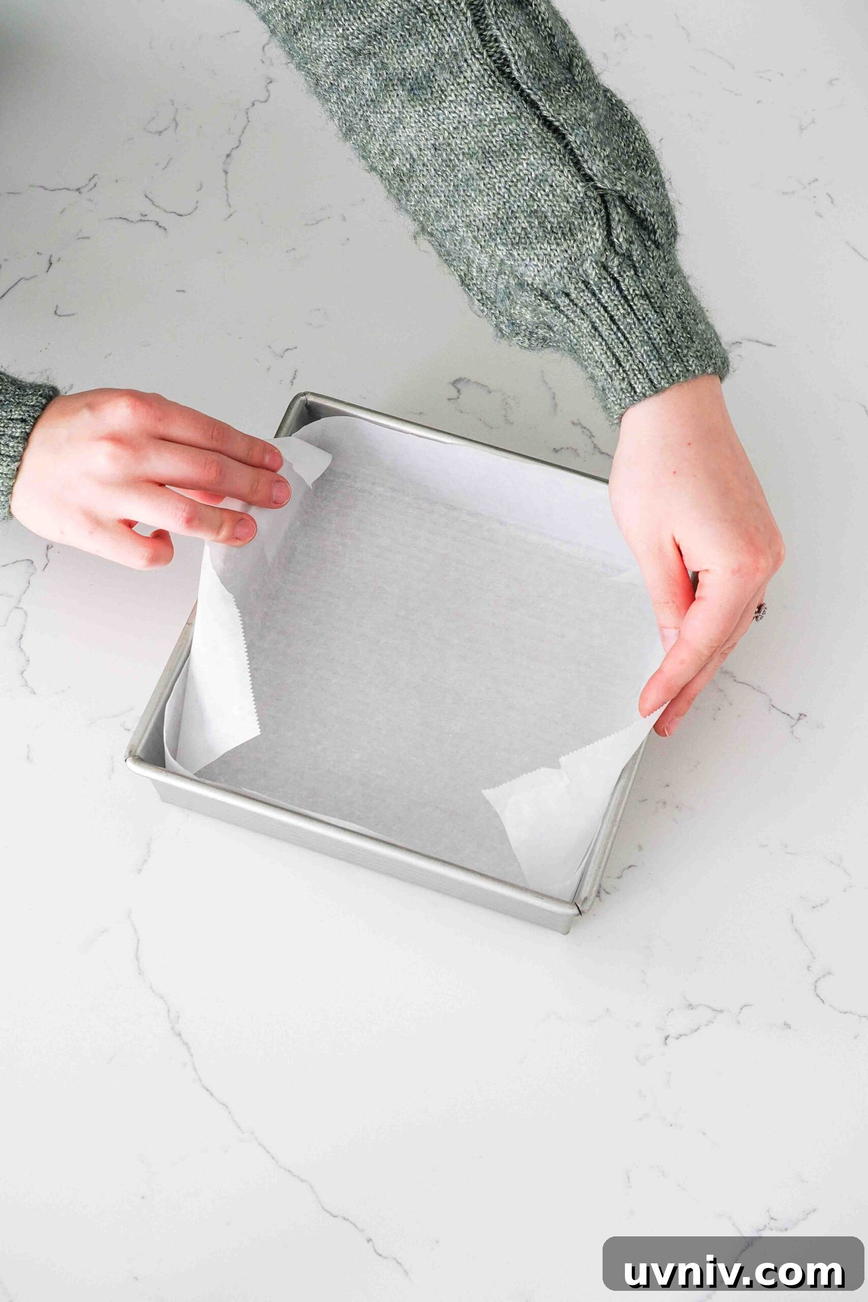 Decadent Peppermint Brownies Recipe for Holiday Baking 4 Two hands line a square metal pan with parchment paper.