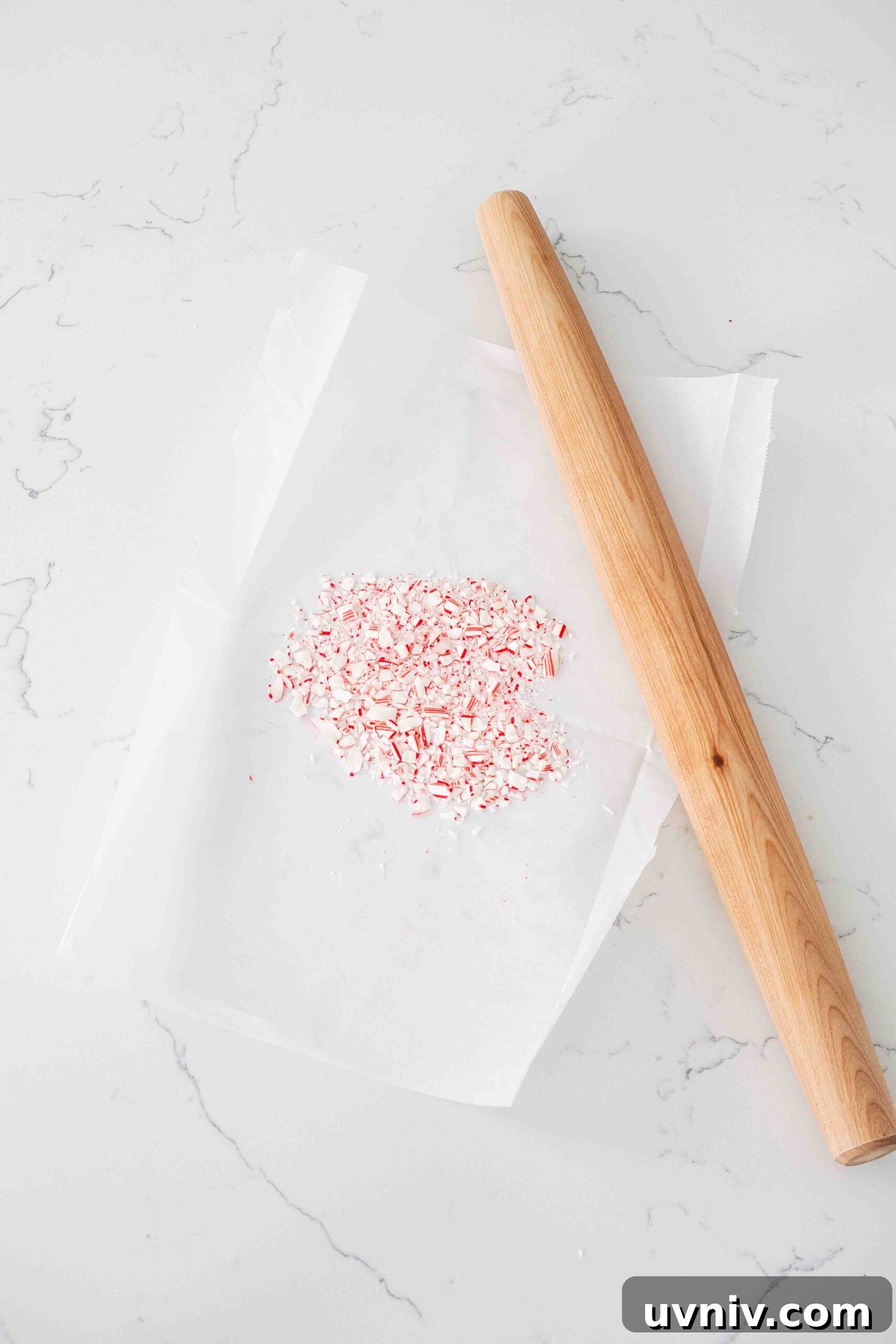 Decadent Peppermint Brownies Recipe for Holiday Baking 5 Crushed candy canes on parchment paper near a rolling pin.