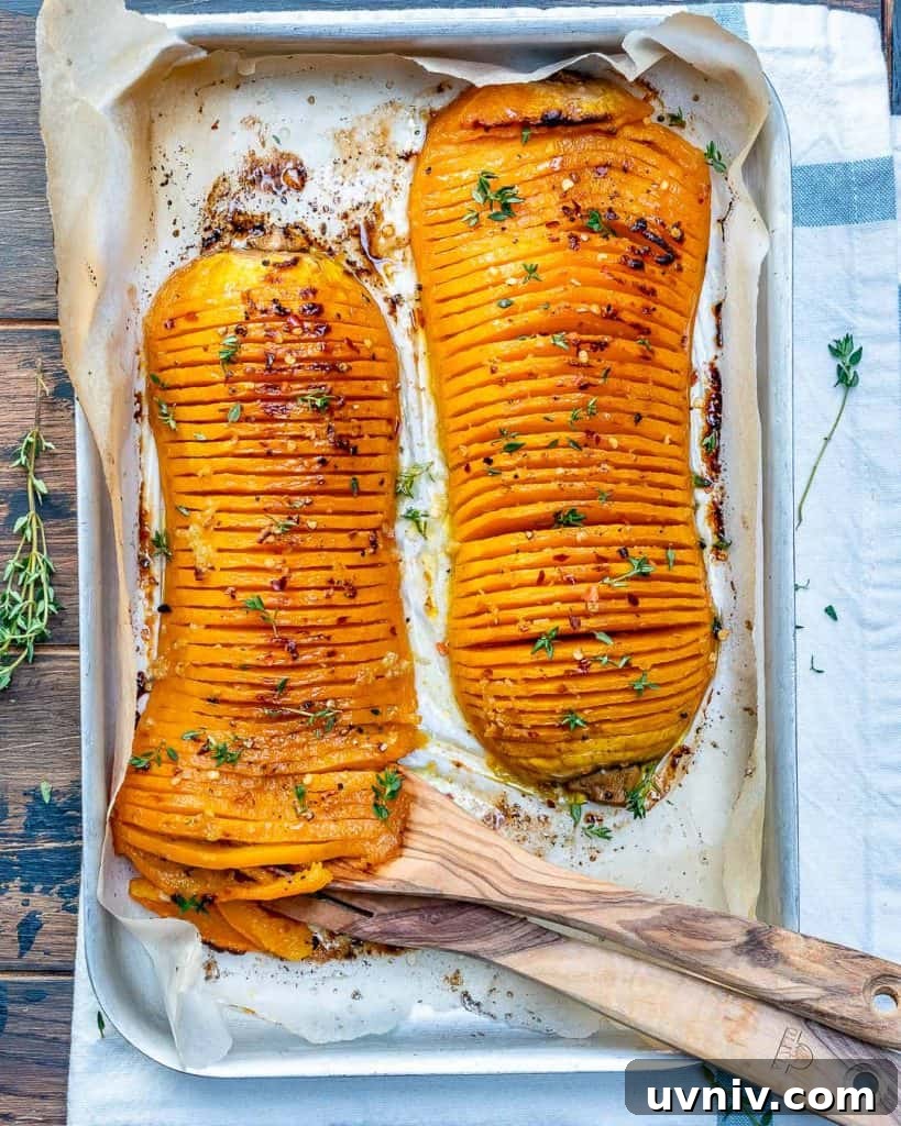 Crispy Hasselback Butternut Squash with Herb Butter 6 top view of two Hasselback butternut squash on a baking pan with wooden spoon on pan to serve