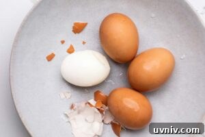Perfect Air Fryer Hard-Boiled Eggs That Peel Easily 12 Air Fryer hard boiled eggs shown in a blue bowl being peeled.