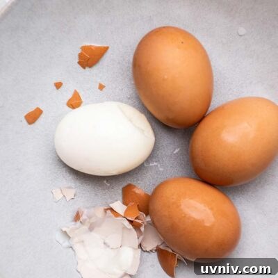 Perfect Air Fryer Hard-Boiled Eggs That Peel Easily 9 Air Fryer hard boiled eggs shown in a blue bowl being peeled.