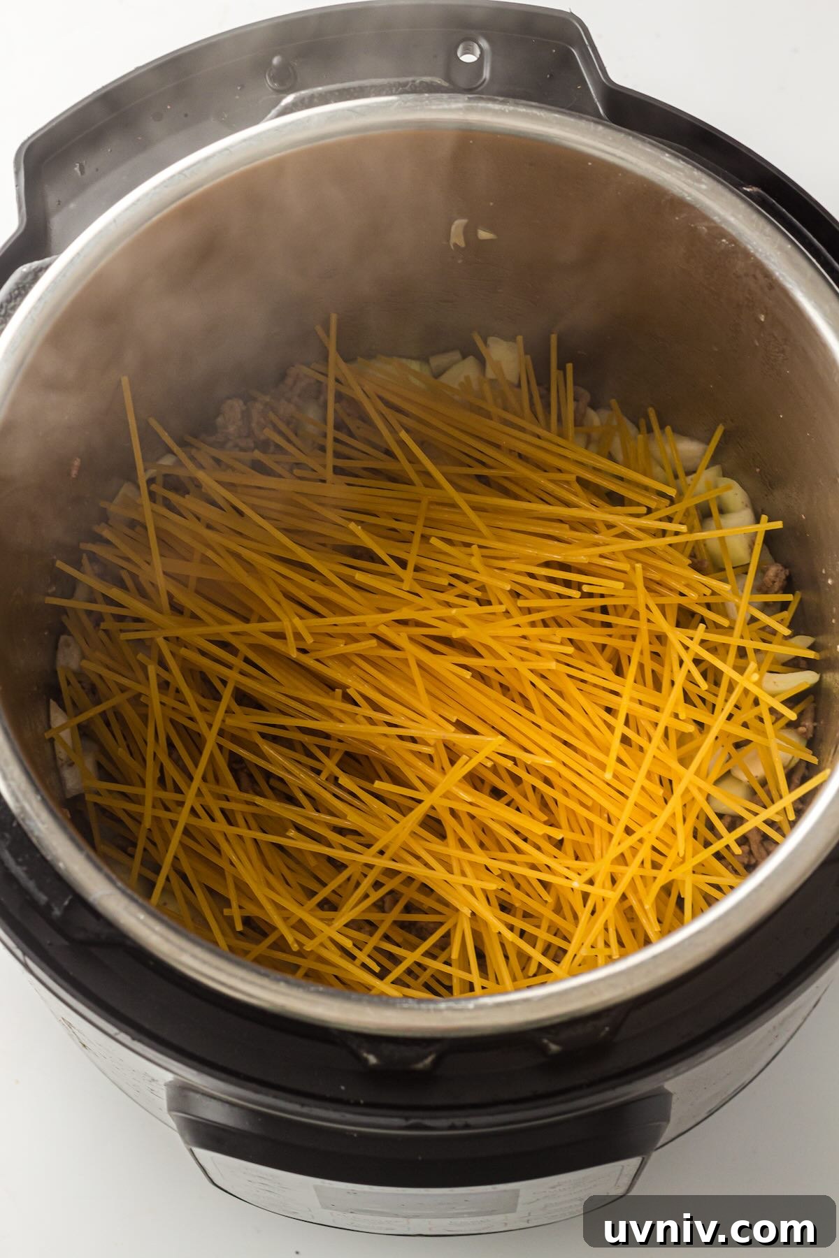 Instant Pot Spaghetti with Savory Meat Sauce 6 Uncooked spaghetti noodles layered in a criss-cross pattern over ground beef in the Instant Pot.