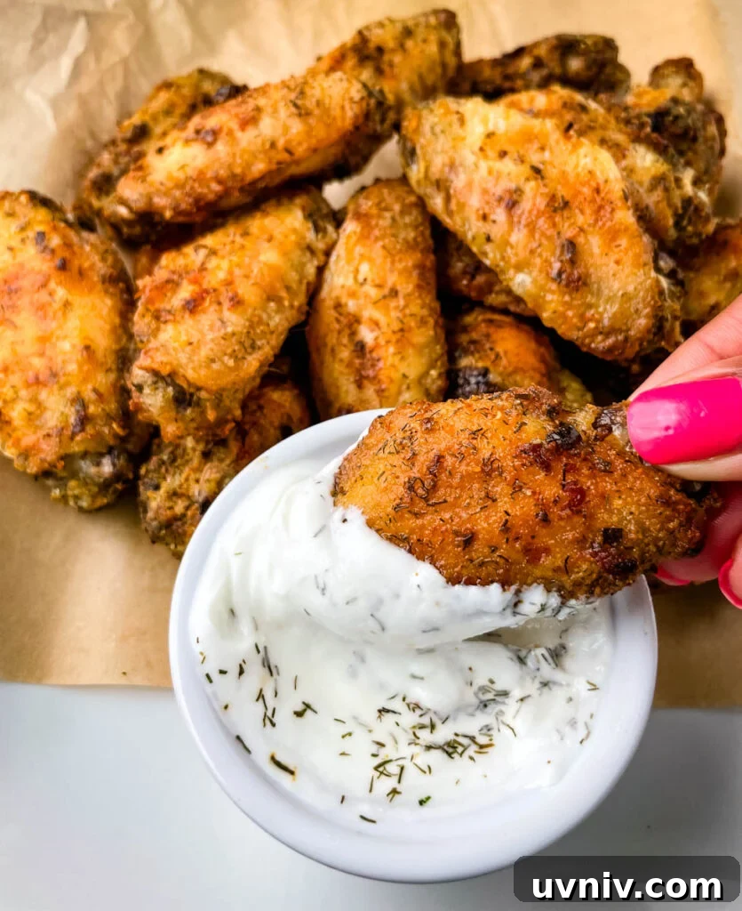 Crispy Ranch Chicken Wings Recipe for Game Day and Parties 8 person holding ranch chicken wing dipped in ranch dressing