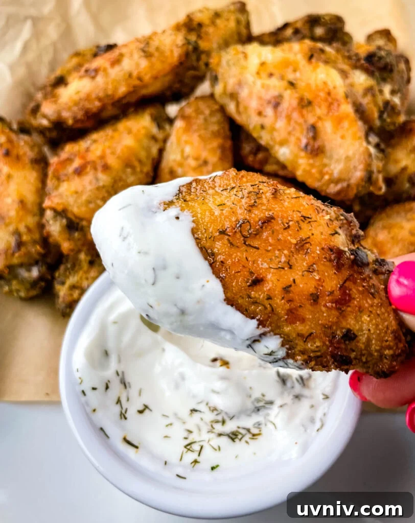 Crispy Ranch Chicken Wings Recipe for Game Day and Parties 9 person holding ranch chicken wing dipped in ranch dressing