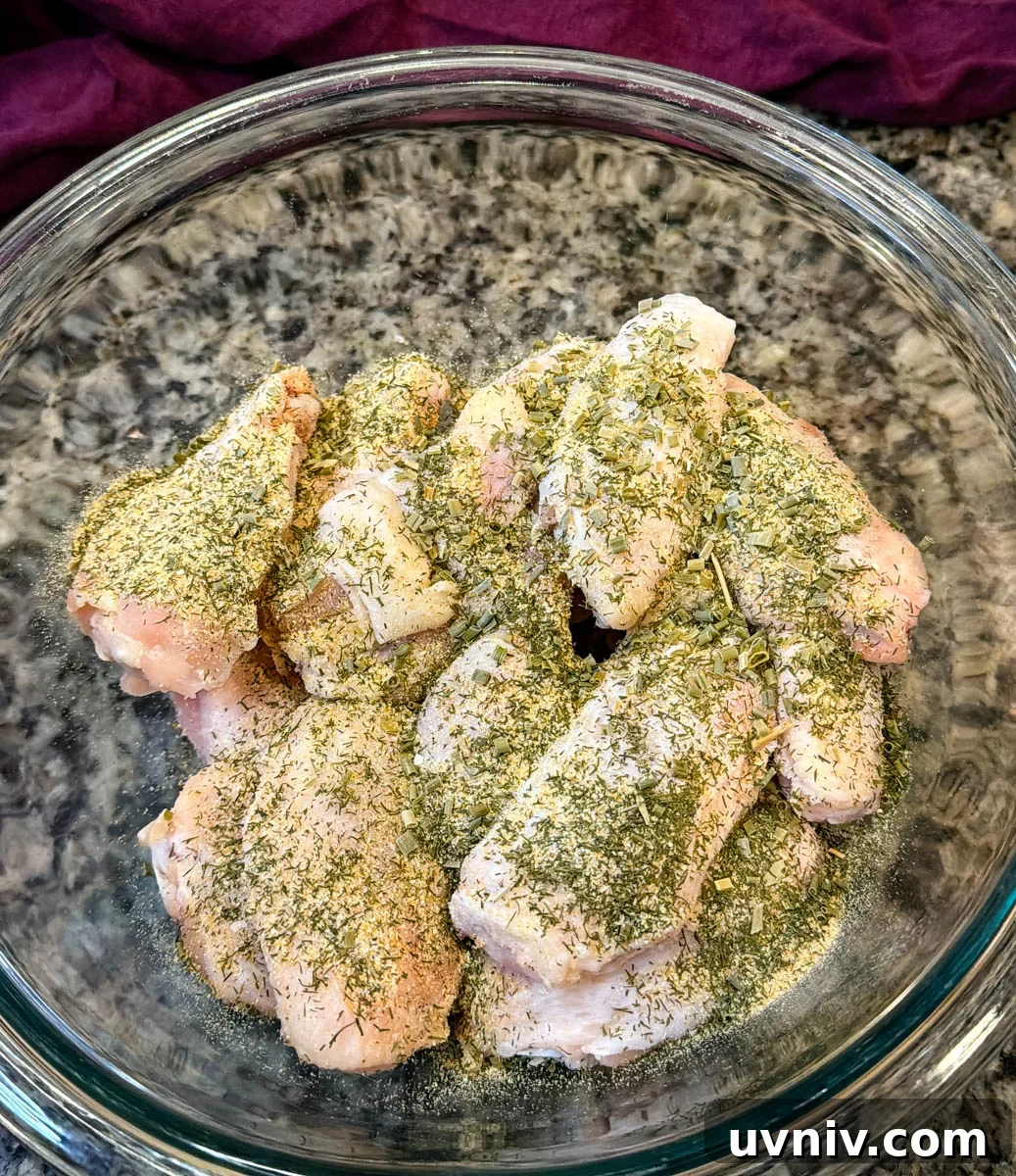 Crispy Ranch Chicken Wings Recipe for Game Day and Parties 3 raw chicken wings in a glass bowl with homemade ranch seasoning