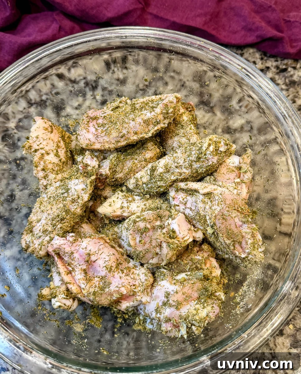 Crispy Ranch Chicken Wings Recipe for Game Day and Parties 4 raw chicken wings with homemade ranch seasoning in a glass bowl