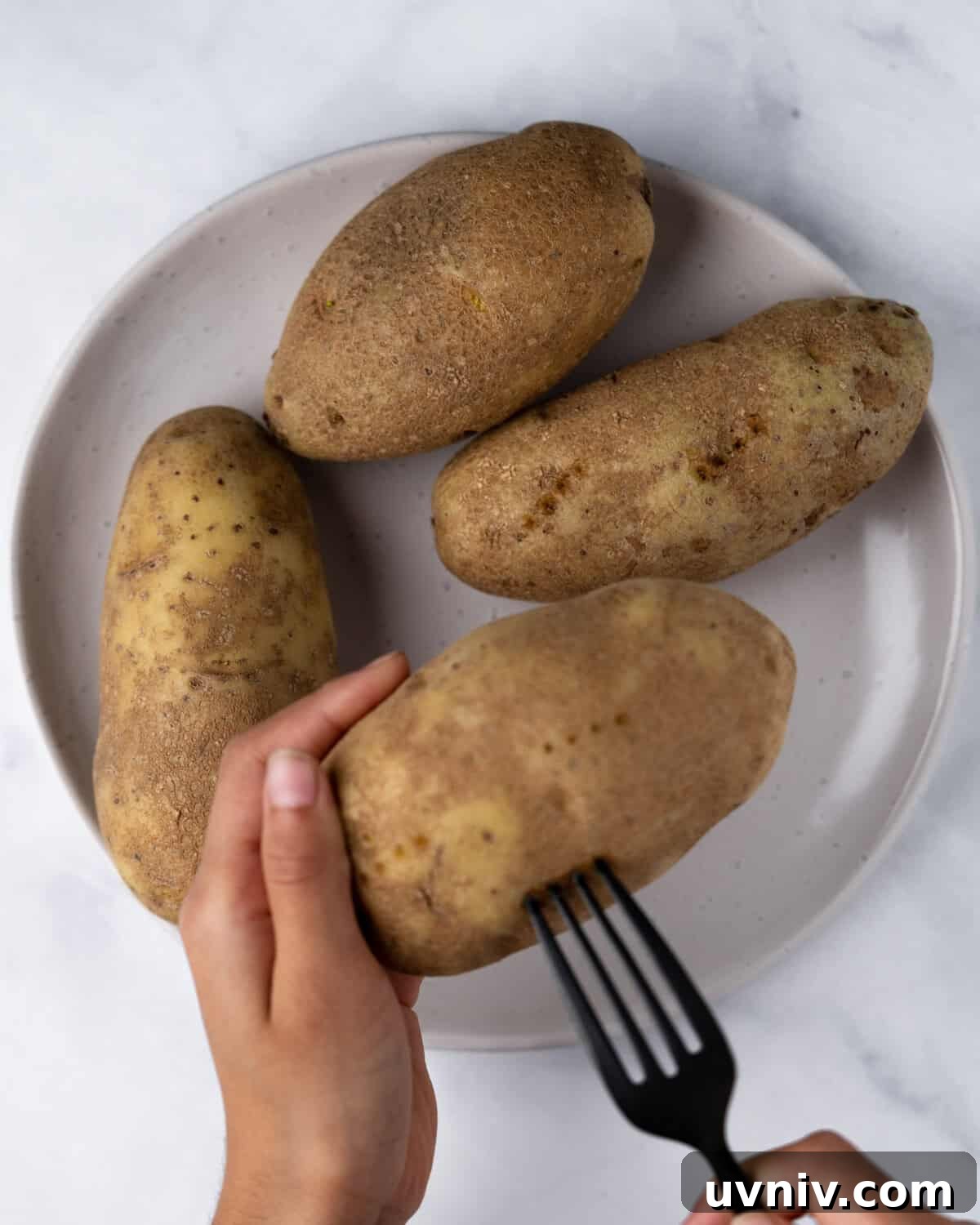 Crispy Air Fryer Potato Skins with Cheesy Bacon Filling 4 Poking holes into potato with fork.