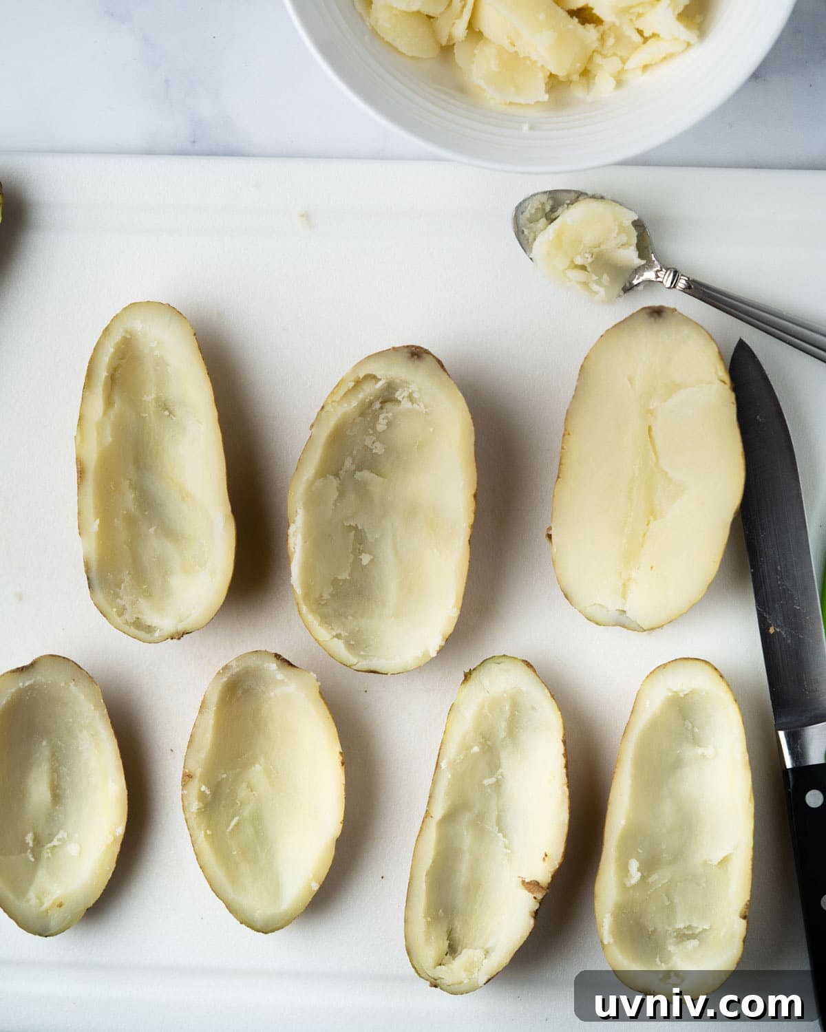 Crispy Air Fryer Potato Skins with Cheesy Bacon Filling 5 scooping out middle of potato with spoon.