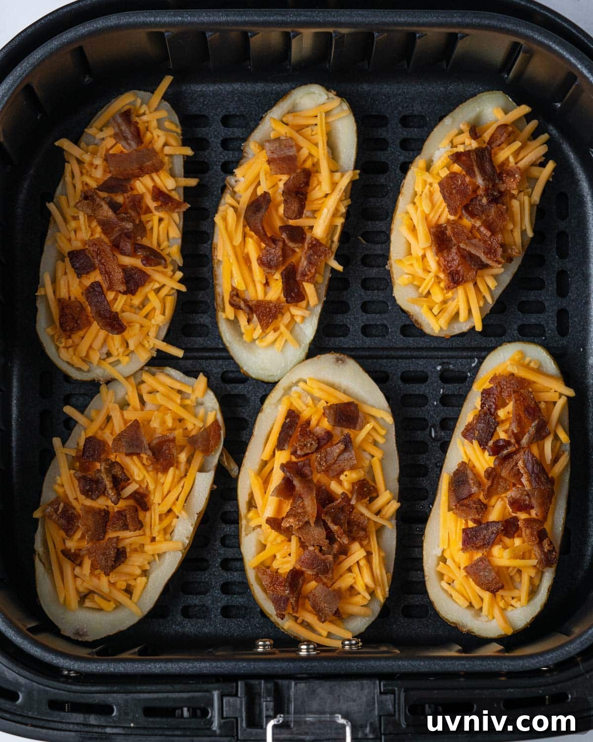Crispy Air Fryer Potato Skins with Cheesy Bacon Filling 7 uncooked potato skins in air fryer basket.