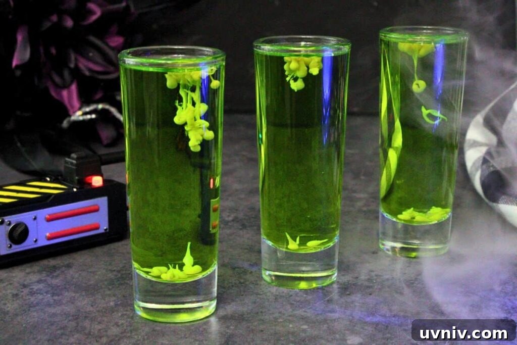Slimer Ghostbusters Shot Recipe for a Spooky Halloween Party 3 three green ghostbusters shots in a row showing floating ectoplasm next to a ghost trap with fog