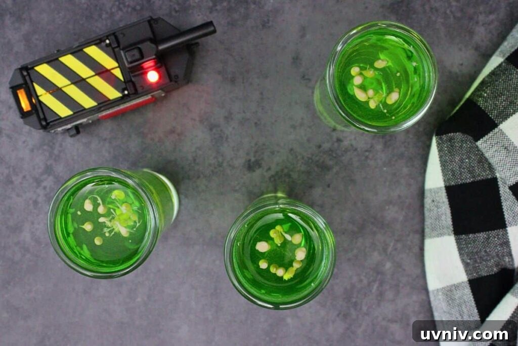 Slimer Ghostbusters Shot Recipe for a Spooky Halloween Party 7 overhead view of three ghostbusters shots as baileys irish cream is added next to a closed ghost trap