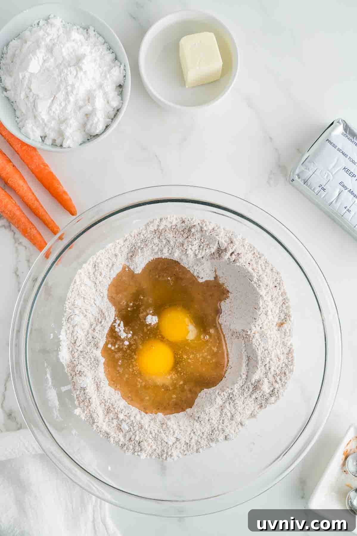 Moist Carrot Cake Loaf with Cream Cheese Glaze 5 An overhead image of creating a well in the middle of dry ingredients and adding eggs and vegetable oil in the middle.