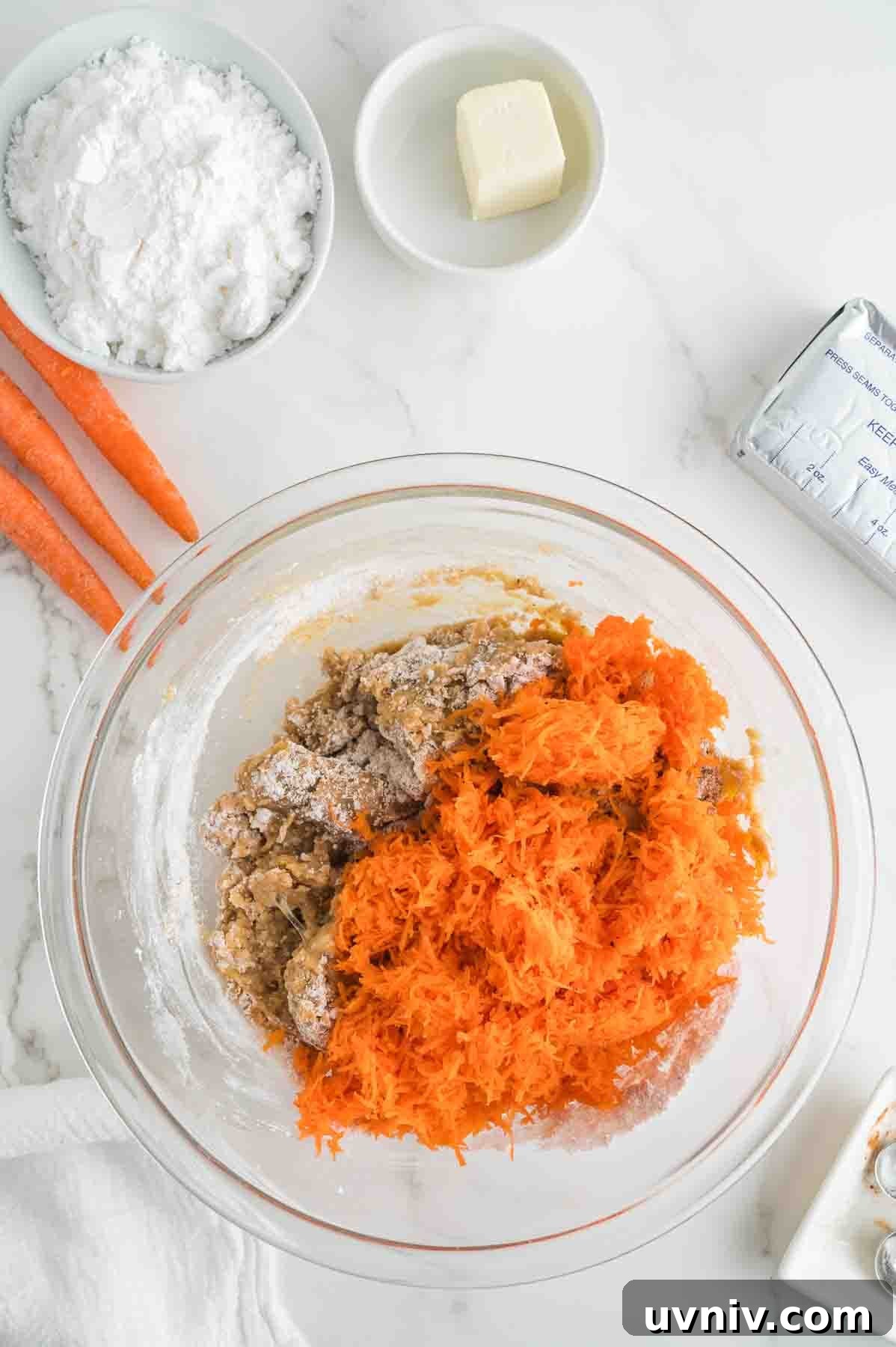 Moist Carrot Cake Loaf with Cream Cheese Glaze 6 An overhead image of adding shredded carrots to the mixture.