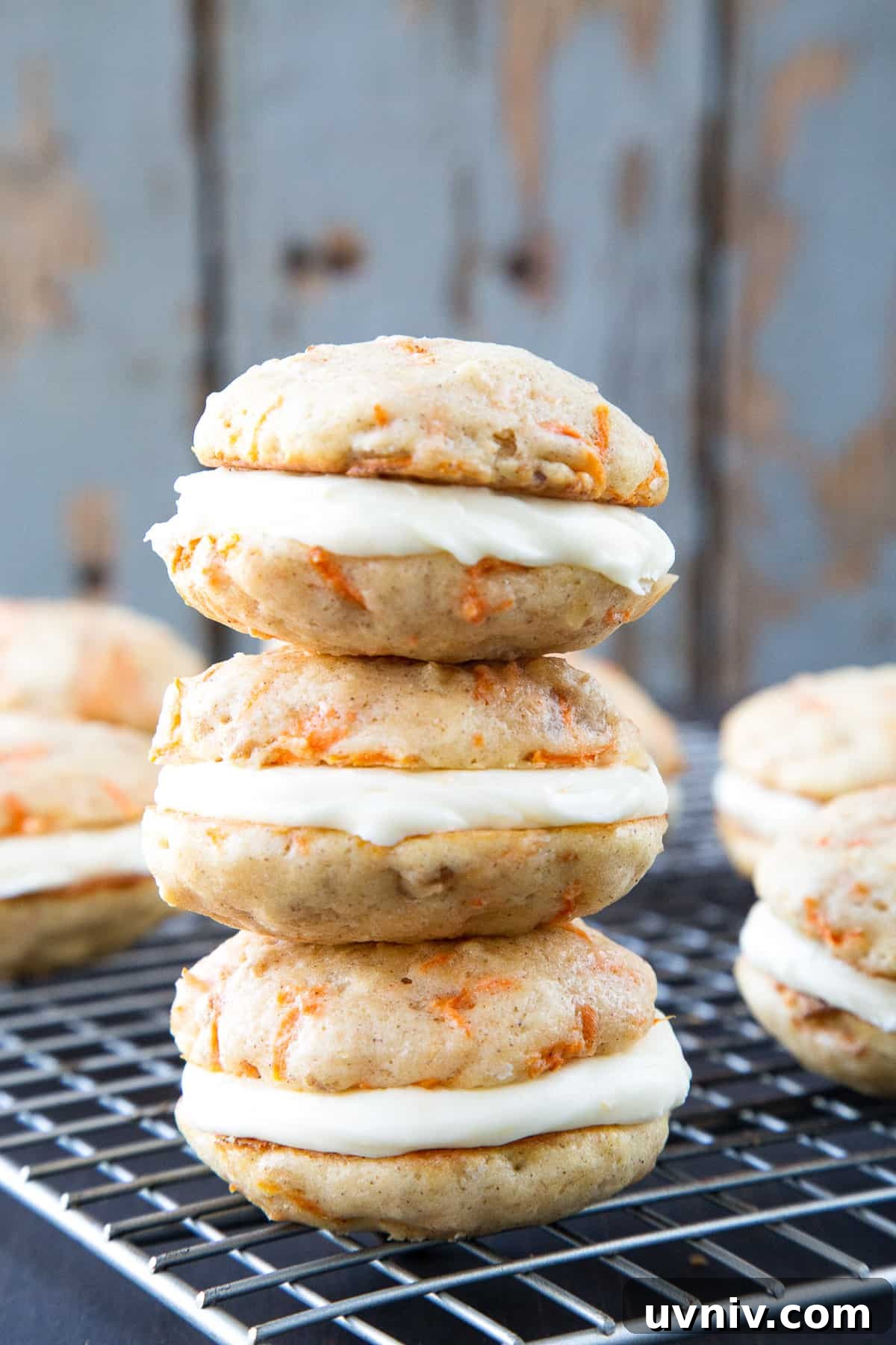 Carrot Cake Whoopie Pies Recipe: Soft Spiced Sandwich Cookies 2 carrot cake whoopie pies with cream cheese frosting stacked on a wire rack.