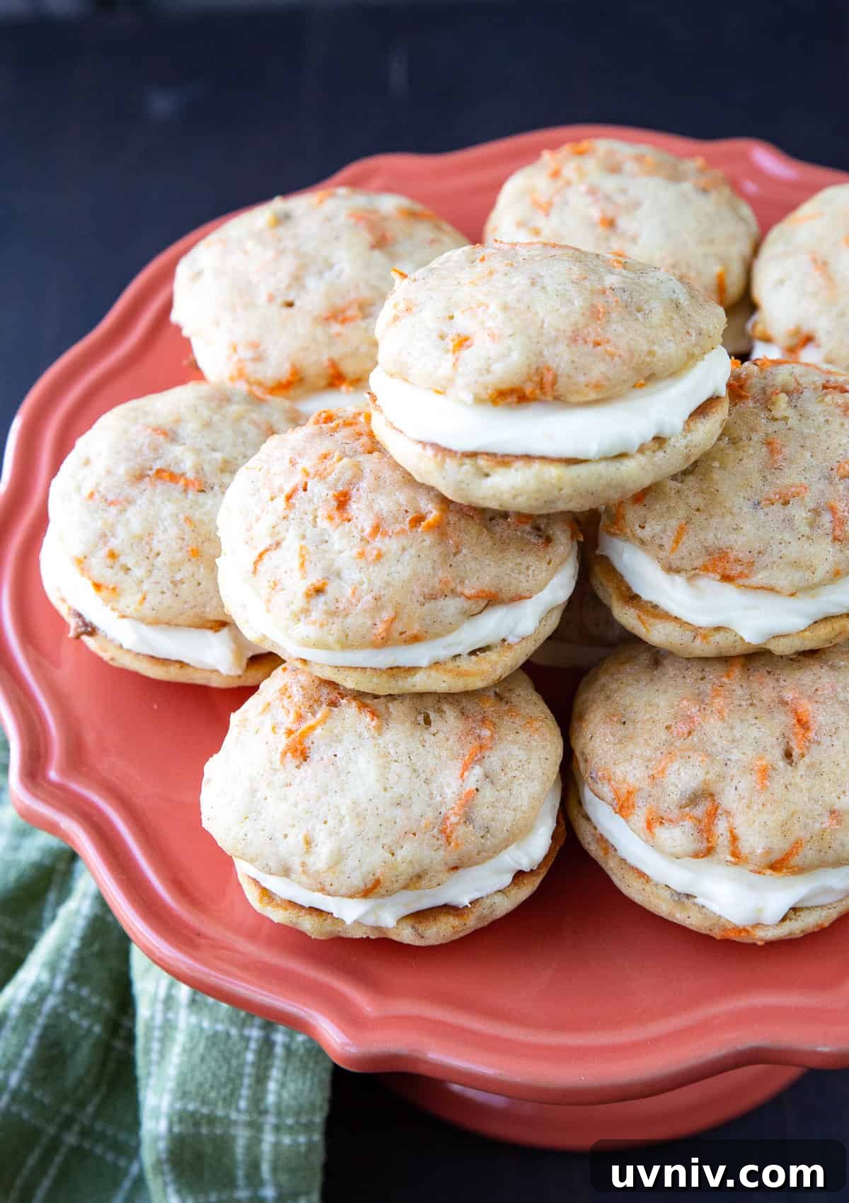 Carrot Cake Whoopie Pies Recipe: Soft Spiced Sandwich Cookies 7 a pile of carrot cake whoopie pies on a pink cake pedestal.
