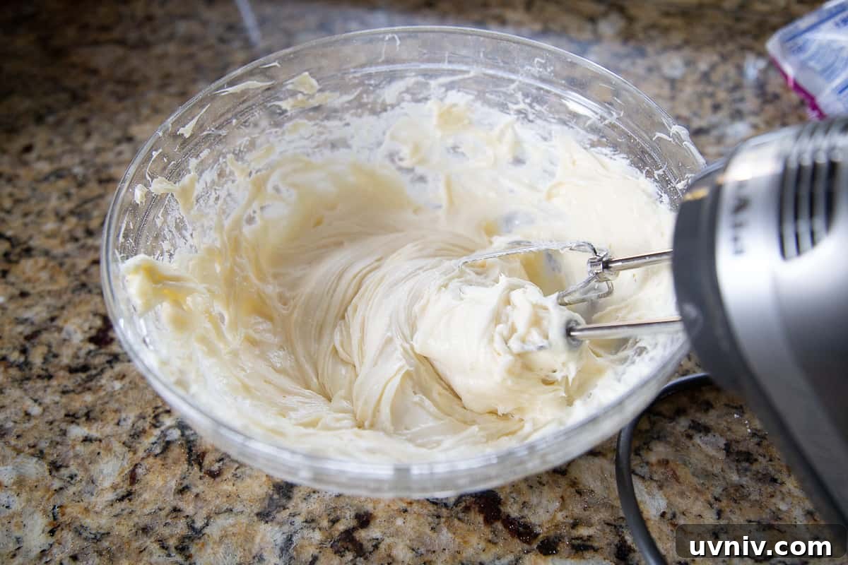 Carrot Cake Whoopie Pies Recipe: Soft Spiced Sandwich Cookies 6 handheld mixer mixing cream cheese frosting in a glass bowl.