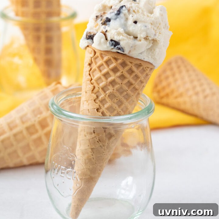 a scoop of homemade butter brickle ice cream on a sugar cone, propped up in a small jelly jar.