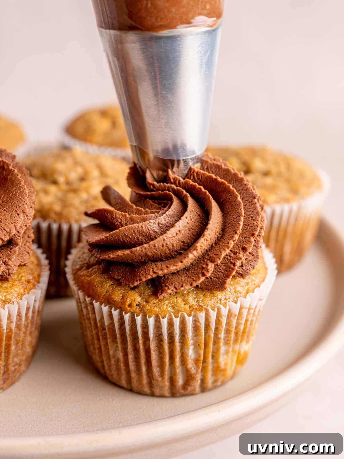 Banoffee Cupcakes Recipe: Caramel Banana Cupcakes with Toffee Frosting 11 Piping whipped chocolate ganache on top of dulce de leche filled banana cupcakes.