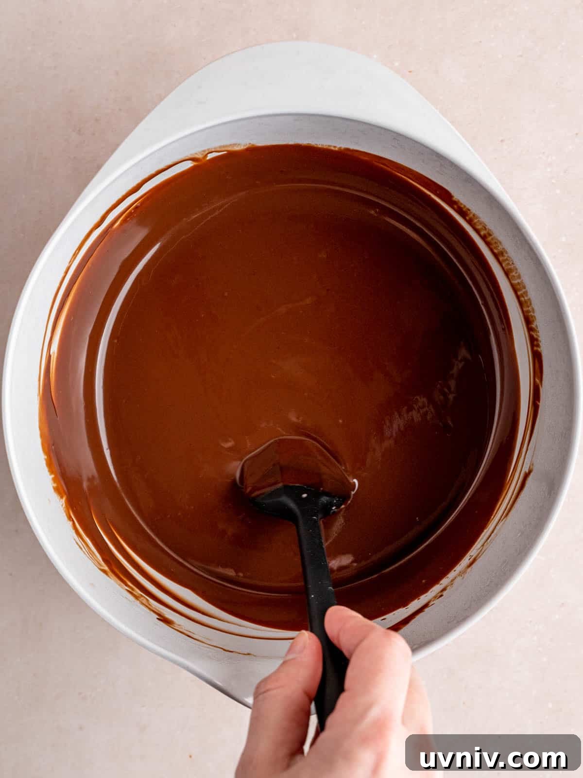 Banoffee Cupcakes Recipe: Caramel Banana Cupcakes with Toffee Frosting 5 Stirring chocolate ganache in a bowl with a spatula.