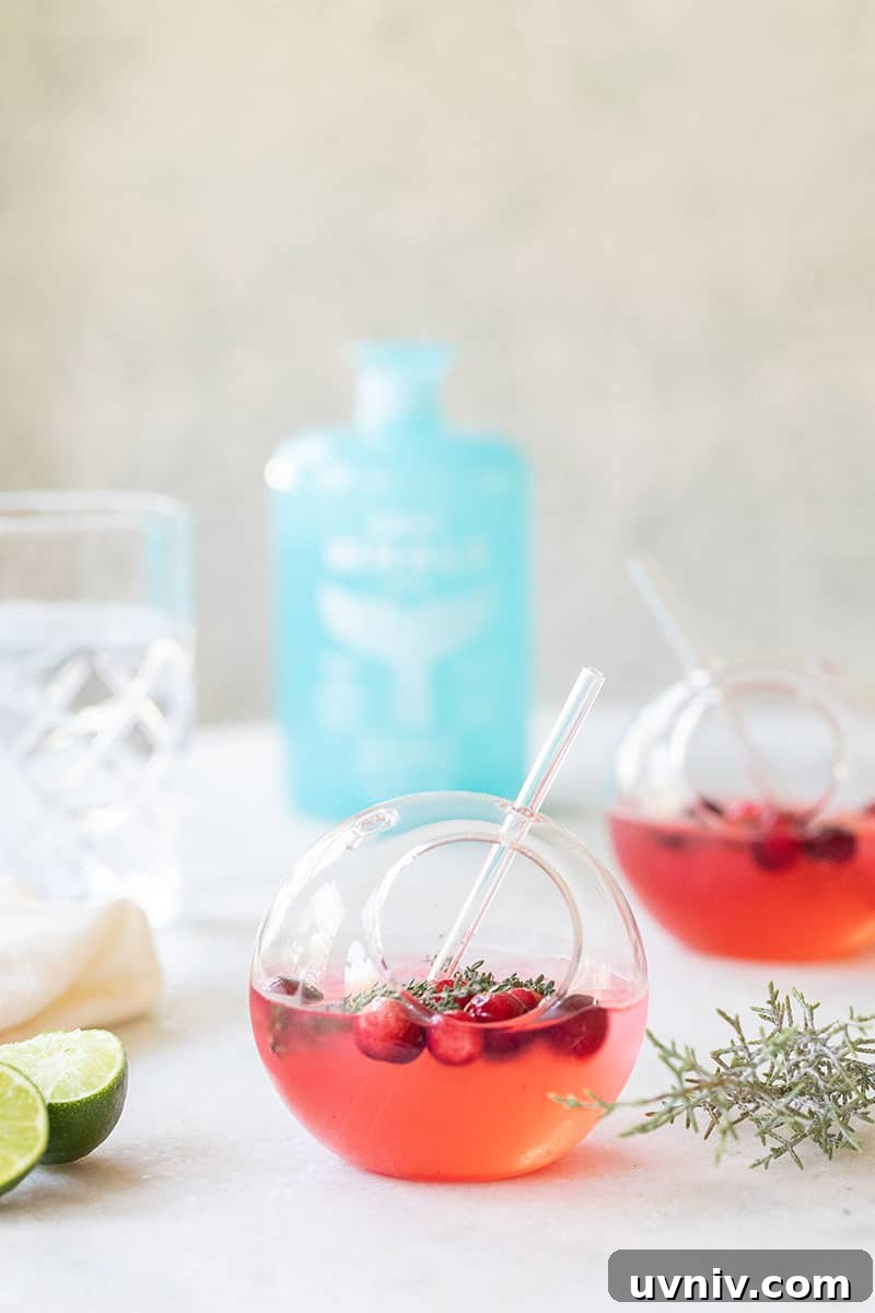 Cranberry and Thyme Gin & Tonic Recipe for Holiday Cocktails 3 Gin and tonic is a round glass with gray whale gin and lime, cranberries and fresh thyme